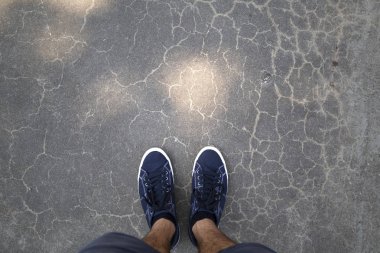 Mavi ayakkabılar asfalt zemin üzerinde duran bir adam bakış.