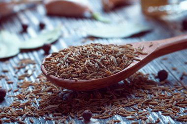 cumin spice in wooden spoon on kitchen table clipart