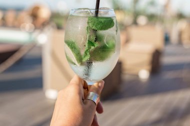 Genç bir kadının elinde köpüklü ve limonlu şeffaf kokteyl. Atmosferik yaz içkisi yakında. Beyaz Rusya, Minsk