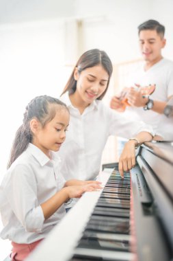 Asya aile, anne ve kızı piyano, baba aile grubu evde, aile ilişkileri için kavram'ın gitar çalmak