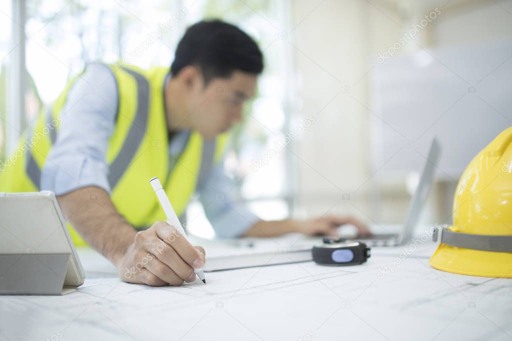 Architect working on blueprint,Engineer inspective in workplace - architectural project, blueprints,Ruler,Calculator,Laptop and divider compass. Construction concept. Engineering tools,Selective focus