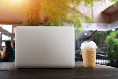 Ahşap masa, masada boş ekran ile dizüstü bilgisayar laptop ve kahve Kupası. kahve dükkanı arka plan bulanık. İş kavramı.