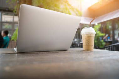 Ahşap masa, masada boş ekran ile dizüstü bilgisayar laptop ve kahve Kupası. kahve dükkanı arka plan bulanık. İş kavramı.
