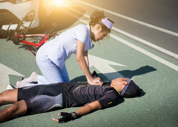 Female nurse helping emergency CPR to asia cyclist injured on the street bike after collision accident car and bike