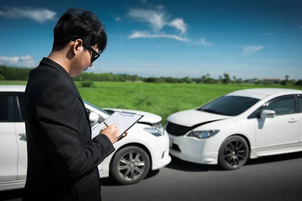 Side view of writing on clipboard while insurance agent examining car after accident, Selective focus