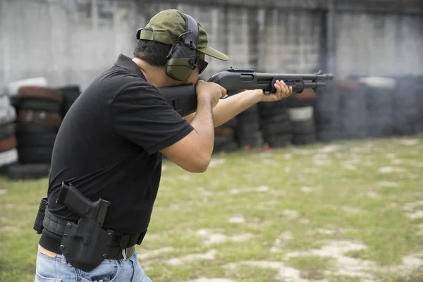 Man shooting shot gun on an outdoor shooting range, selective focus