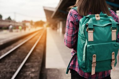 Gezgin kadın yürüyüş ve beklediği Tren demiryolu platformu, güneş ışık parlama, seçici odak