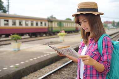 Genç kadın yolcunun sırt çantası ve Tren İstasyonu ve seyahat planlıyorsanız, seyahat kavramı için haritada seyir şapka ile