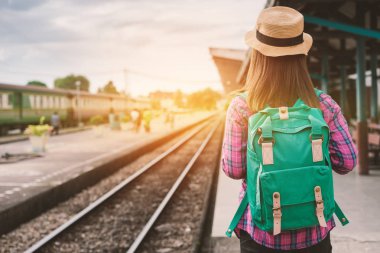 Gezgin kadın yürüyüş ve beklediği Tren demiryolu platformu, güneş ışık parlama, seçici odak