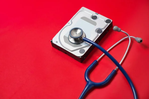 听诊器和硬盘驱动器上的红色背景 计算机硬件诊断与修复概念 — 图库照片