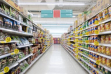 Renkli rafları ve tanınmayan müşterileri olan soyut bulanık süpermarket koridoru