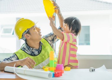 Planı üzerinde çalışan mimar. İşyeri ve koruyucu inşaat kask eğitim, Asyalı küçük çocuk öğrenme mühendislik ve mimari plan babasının üzerine Mimarlar