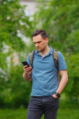 ormanda yürüyüş sırasında cep telefonu kullanan genç adam