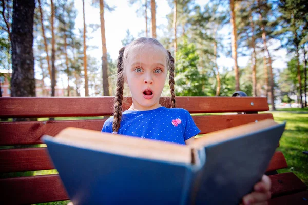 Linda niña está leyendo un libro al aire libre — Foto de Stock