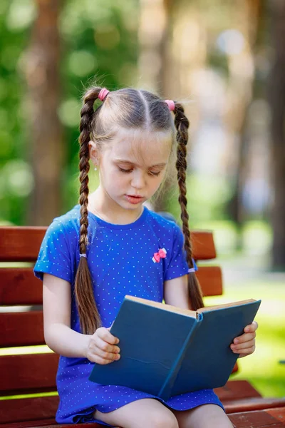 Retrato de colegiala en un libro de lectura de banco. Antecedentes parque . — Foto de Stock