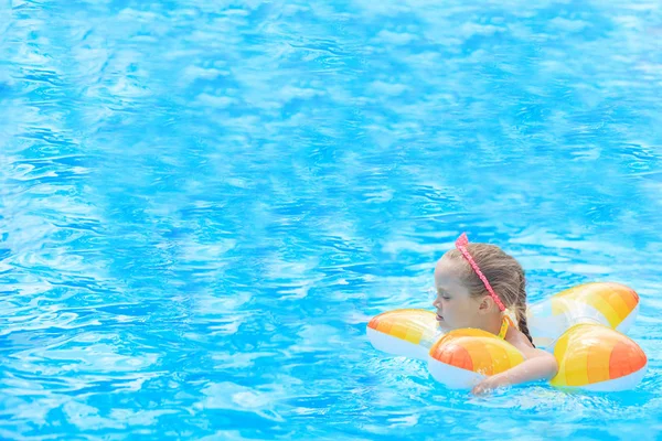 Feliz niña jugando con el anillo inflable colorido en la piscina al aire libre en el día caliente del verano. Los niños aprenden a nadar. Juguetes de agua infantil. Los niños juegan en el resort tropical. Vacaciones familiares en playa. — Foto de Stock