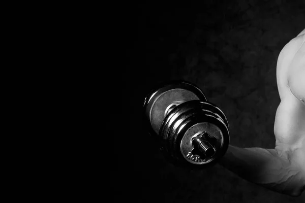 Parte di un corpo umido mans con manubri in metallo su uno sfondo scuro — Foto Stock