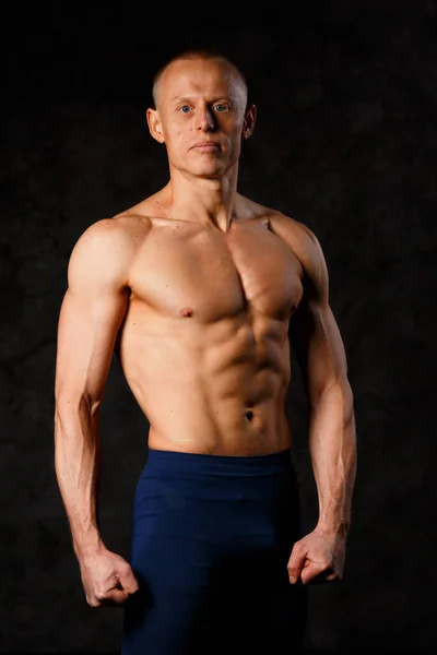 Bonito homem muscular posando no fundo escuro — Fotografia de Stock