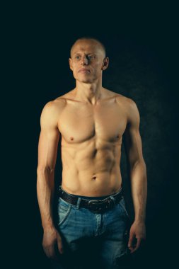 Yakışıklı ve kaslı adam koyu arka planda. Tonda