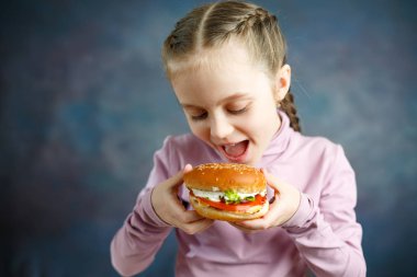Küçük şirin kız çocuk fast food yemek kavramı bir kafede hamburger yemek