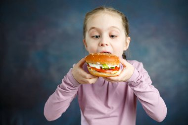 Güzel sevimli küçük beyaz sarışın kız Hamburger ile