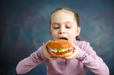 Burger yemek oldukça Amerikan küçük kız. Sağlıksız yeme kavramları. Kapalı Studio poz
