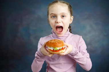 Güzel sevimli küçük beyaz sarışın kız Hamburger ile