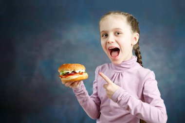 Güzel şirin küçük beyaz bir kız gösterir A Hamburger onun elinde değil.