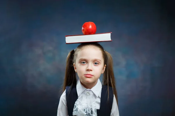 Aranyos iskoláslány tart alma könyv a fej portré — Stock Fotó