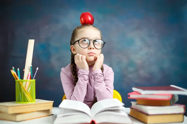 思いやりのある小学生の少女研究写真 三つ編みがかわいい小さな学習机だと思う質問に座っています スマート白人の子供は頭に赤いリンゴを保持します 学校システム教育概念ショット — ストック写真