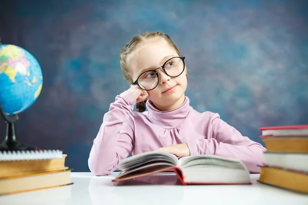 美しい小さな女子高生が思慮深く本を読みます 小学校女子高生はかわいいと思う質問を宿題します デスク教育システム概念で眼鏡夢でスマートな白人子 — ストック写真