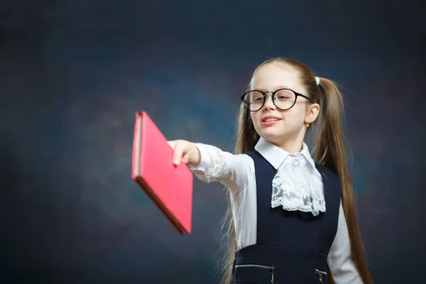 Jong schoolmeisje passeren houden boek knipoog met één oog — Stockfoto