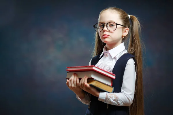 Fröhliche Grundschülerin hält Bücherstrauß in der Hand — Stockfoto