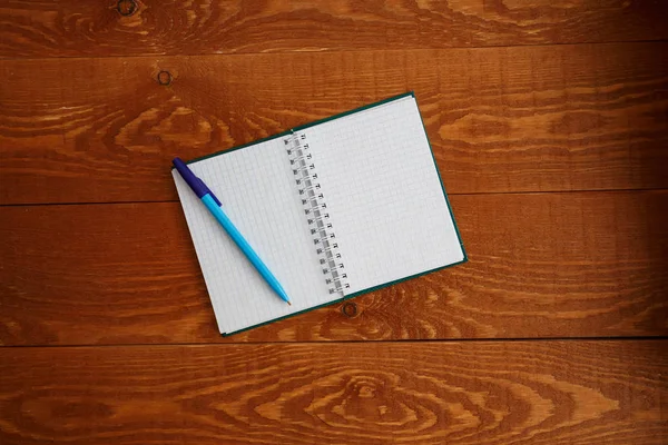 Cuaderno en blanco y pluma en madera escritorio vista superior — Foto de Stock