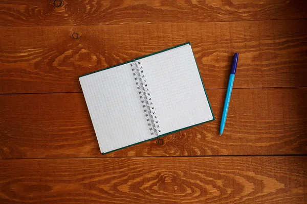 Cuaderno en blanco y pluma en madera escritorio vista superior — Foto de Stock