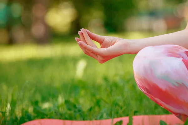 Young woman sitting on yoga map and being meditation pose in the beautiful park , Close up body part , hand part with nice lighting, copy space,healthy concept