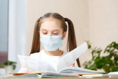 Uzaktan eğitim. Tıp maskeli kız evde ödev yapıyor. Karantina..