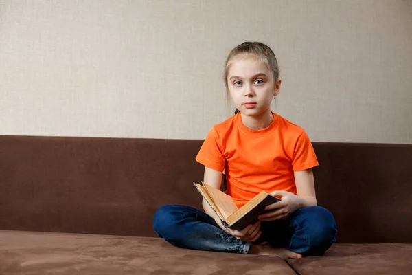 白人の女の子は自宅で本を読んでソファに座って — ストック写真