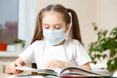 Tıp maskeli küçük bir kız kitap okuyor. Karantina, evde kal. The Who 'nun tavsiyesi. Coronavirüs Salgını Konsepti