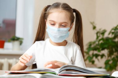 Tıp maskeli küçük bir kız kitap okuyor. Karantina, evde kal. The Who 'nun tavsiyesi. Coronavirüs Salgını Konsepti
