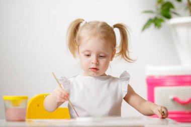 Güzel küçük kız odasında suluboya resimler çiziyor. Çocuk, yaratıcılıkla meşgul. Küçük Sanatçı.