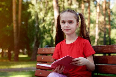 Kitap okuyan güzel bir kızın açık hava portresi.