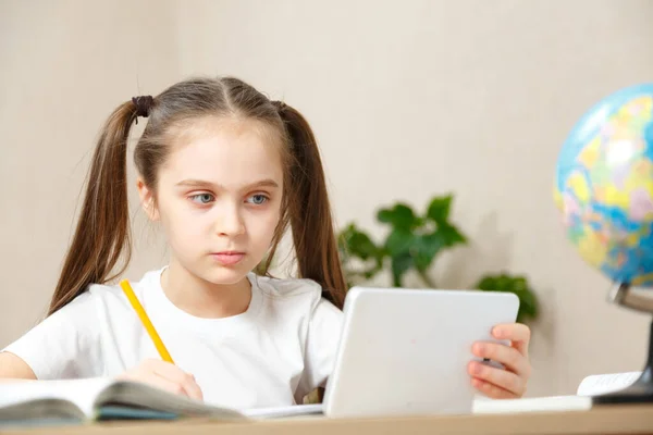 Distance learning online education. Schoolgirl studying at home with notebookand doing school homework.Girl doing homework with joy and interest. Communication social distance during quarantin
