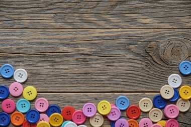 Renkli dikiş düğmeleri ahşap arkaplanda metin için alanı olan bir çerçeve oluşturur.