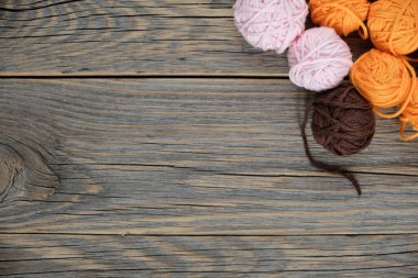 Ahşap masa, örgü örmek, örgü örmek ve kanca örmek için bir sürü renkli iplik. Örgü ve ipliklerle donatılmış arka plan.