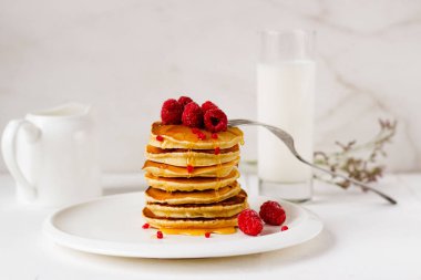 Beyaz plaka üzerinde bal ve ahududu ile krep uzun yığını. Tüm aile için kahvaltı 