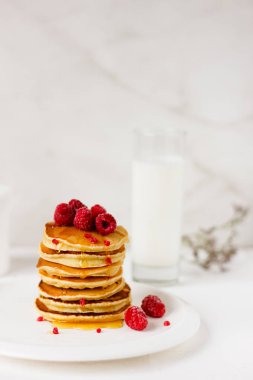 Beyaz plaka üzerinde bal ve ahududu ile krep uzun yığını. Tüm aile için kahvaltı 