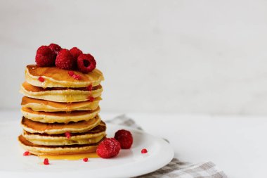 Beyaz plaka üzerinde bal ve ahududu ile krep uzun yığını. Tüm aile için kahvaltı 