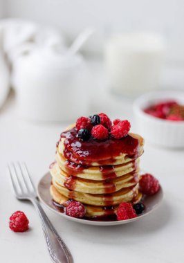 Beyaz arka planda ahududu ve meyve sosu ile lezzetli krep ile plaka. Üstteki görünüm kopyası alanı