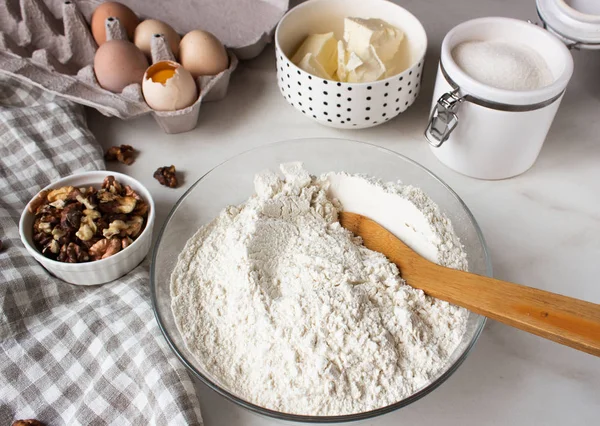 Ingredients for baking cake. Eggs, flour, sugar and whisk, butter nuts.